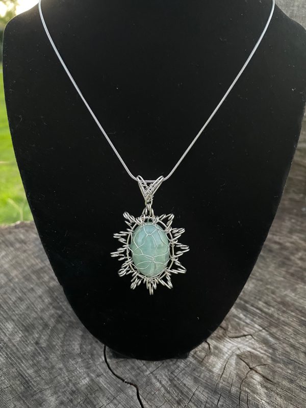 Aquamarine Cabochon stone with silver colour wire. The pendant shape is like a star